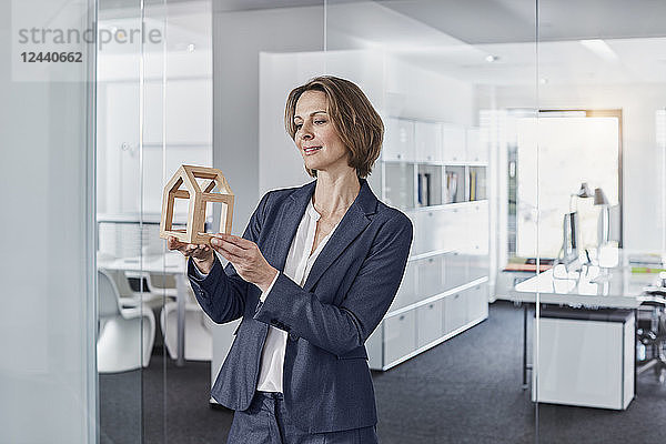 Smiling businesswoman looking at architectural model in office