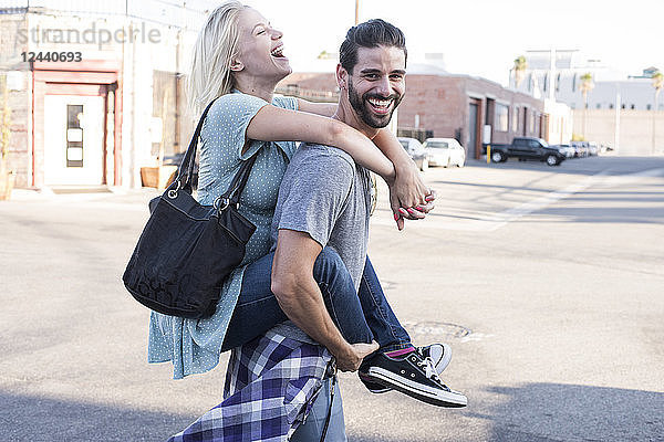 Happy young man carrying girlfriend piggyback