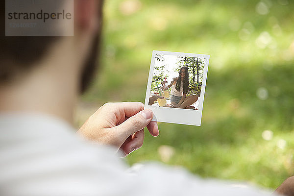 Man holding instant photo of his girlfriend  partial view