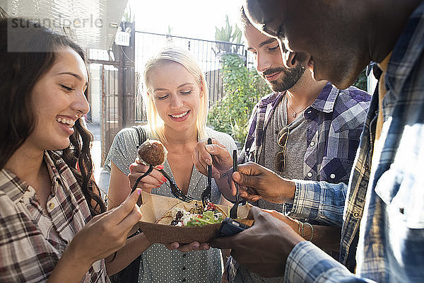 Happy friends sharing takeaway food outdoors