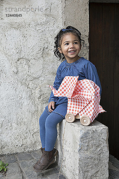 Little girl sitting on wall  origami elephant with rolls