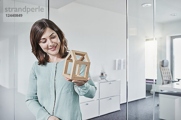 Smiling young businesswoman looking at architectural model in office