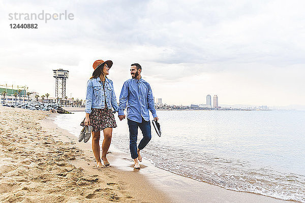 Spain  Barcelona  couple walking barefoot on the beach