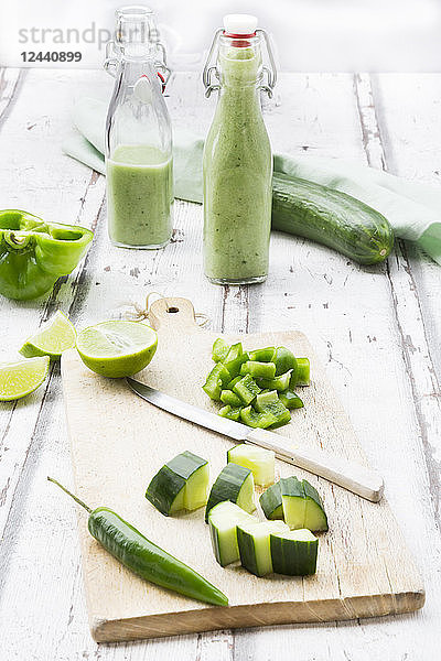 Glass bottle of homemade green Gazpacho and ingredients