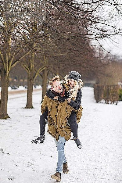 Young man giving his girlfriend a piggyback ride in winter