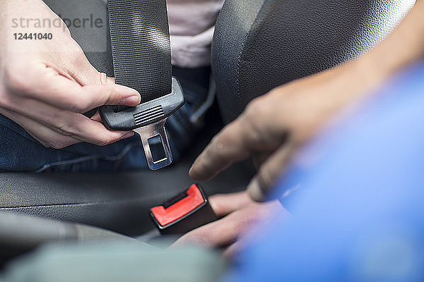 Male hands in car fastening safety belt
