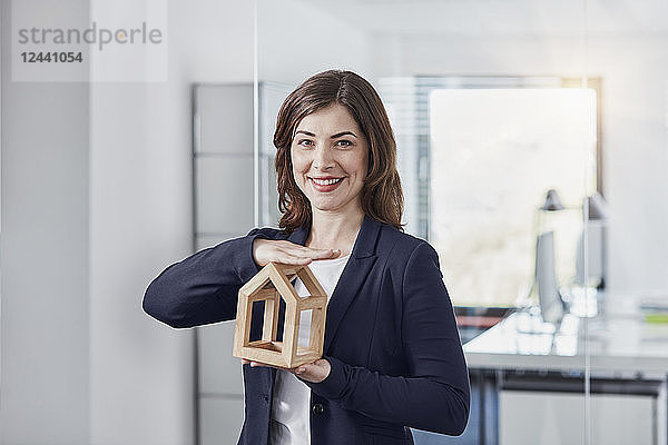 Portrait of smiling young businesswoman holding architectural model in office
