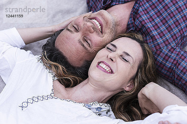 Happy affectionate couple lying on a blanket