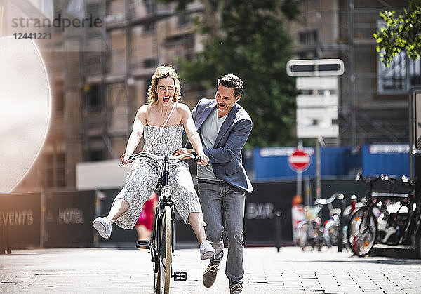 Happy carefree couple with bicycle in the city