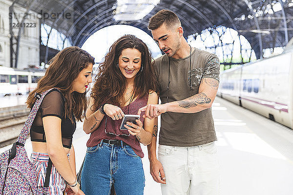 Friends with cell phone on train station platform