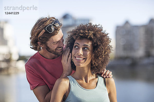 Happy young couple  man whispering into woman's ear