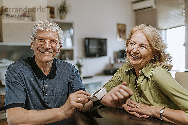 Smiling senior couple with blood pressure gauge