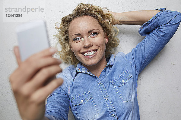 Portrait of smiling blond woman taking selfie with smartphone