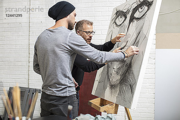 Artist discussing drawing with man in studio