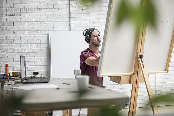 Artist wearing headphones drawing in studio