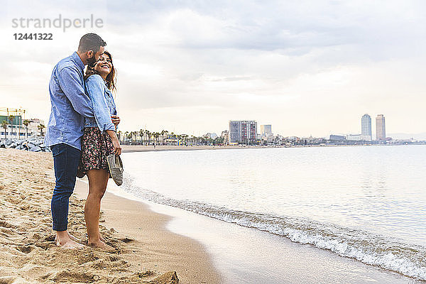 Spain  Barcelona  couple standing barefoot on the beach