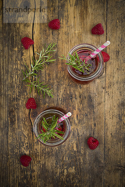 Two glass bottles of homemade raspberry lemonade flavoured with rosemary