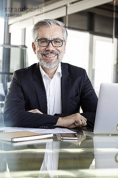 Portrait of smiling businessman at desk in office