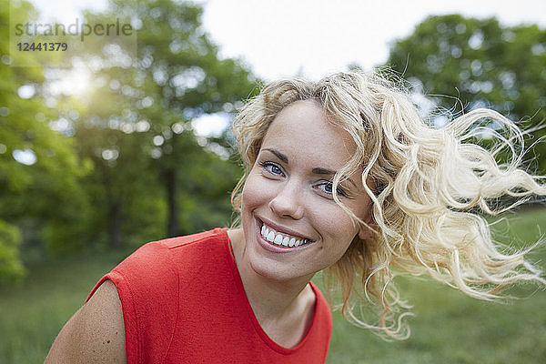 Portrait of smiling blond woman wearing red t-shirt outdoors