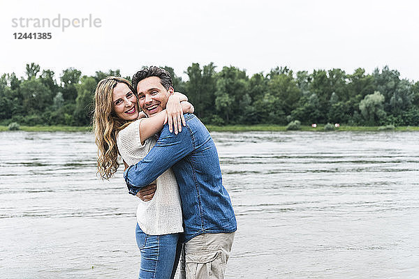 Portrait of happy couple hugging at the riverside