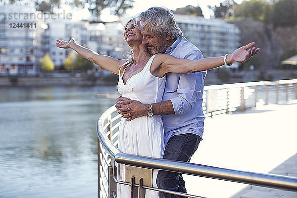 Senior couple taking a city break  embracing at a railing