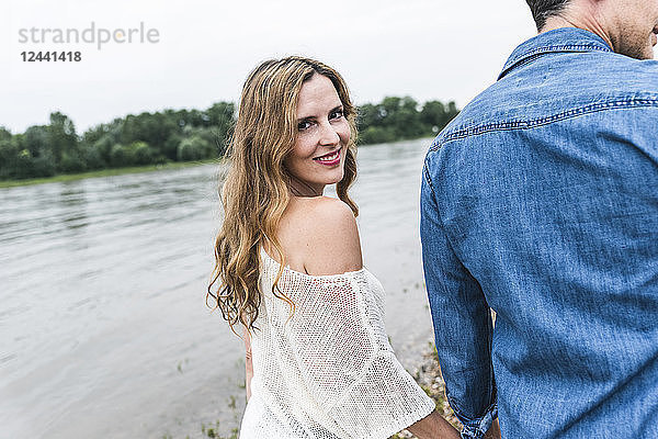 Smiling woman walking hand in hand with man at the riverside