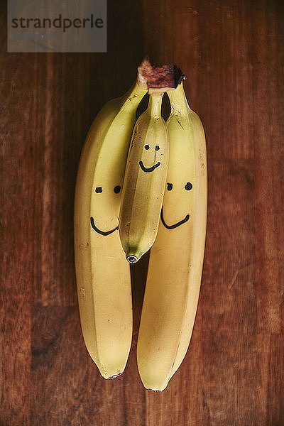 Bunch of two large and one small bananas with smiley faces