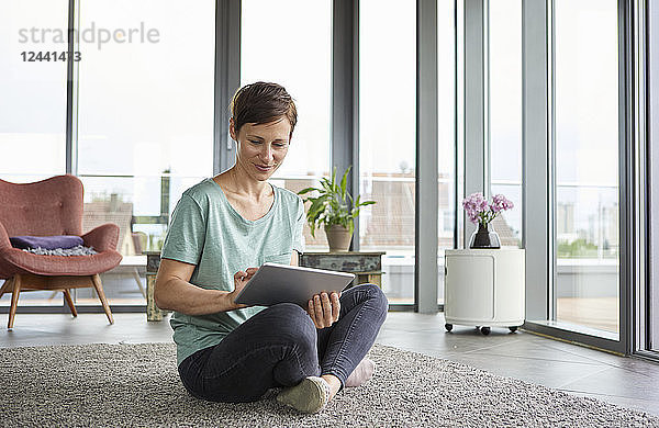 Woman sitting on the floor at home using tablet