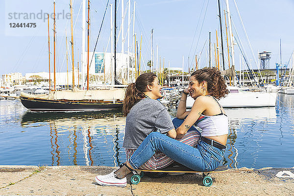Young woman and teenage girl with a skateboard at marina