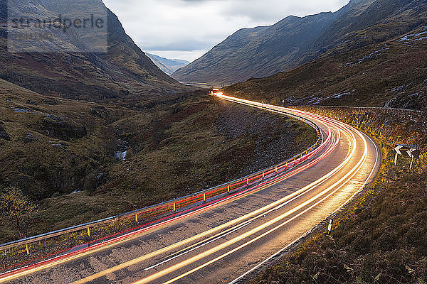 UK  Scotland  car light trails on scenic road through the mountains in the Scottish highlands near Glencoe at dusk
