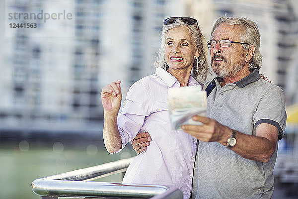 Senior couple taking a city break  holding map