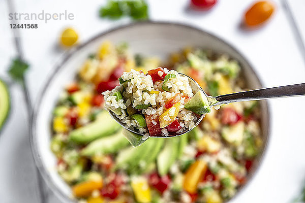 Spoon of bulgur salad with bell pepper  tomatoes  avocado  spring onion and parsley