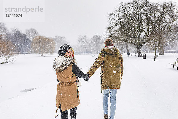 Happy teenage girl strolling with her boyfriend in park on snow day