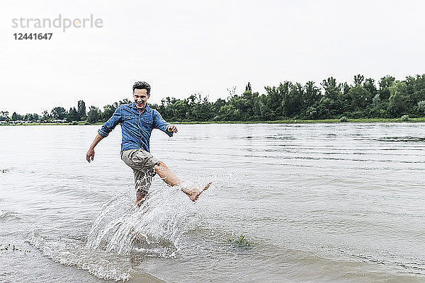 Laughing man splashing water in a river