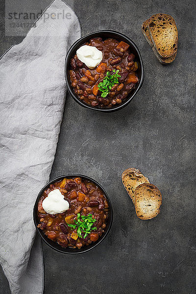 Two bowls of Chili con Carne with fresh coriander and sour cream