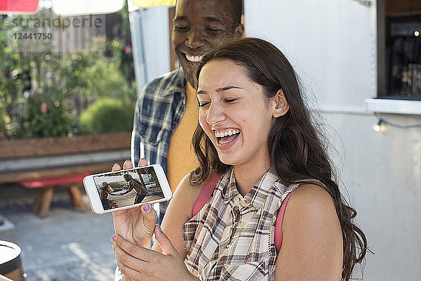 Happy young woman with boyfriend showing cell phone picture