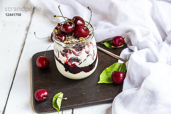 Glass of natural yoghurt with cherries  cherry jam and granola