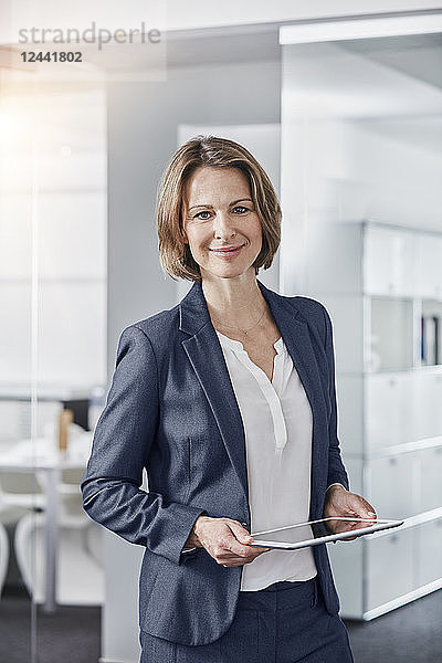 Portrait of smiling businesswoman holding tablet in office