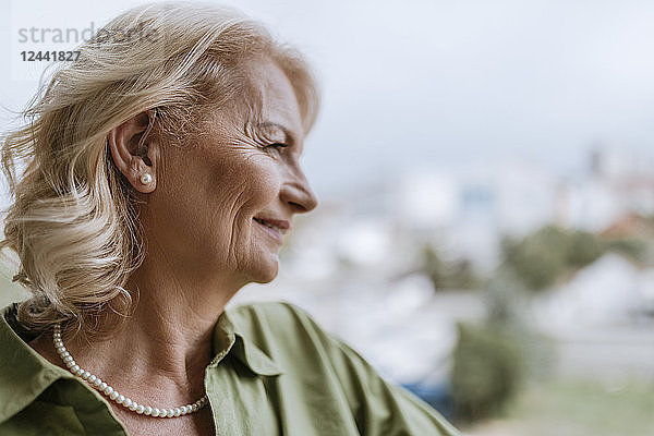Smiling senior woman with hearing aid outdoors