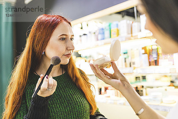 Two women in a cosmetics shop trying make up