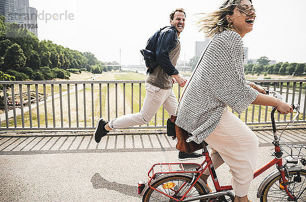 Happy couple crossing a bridge with bicycle and by foot