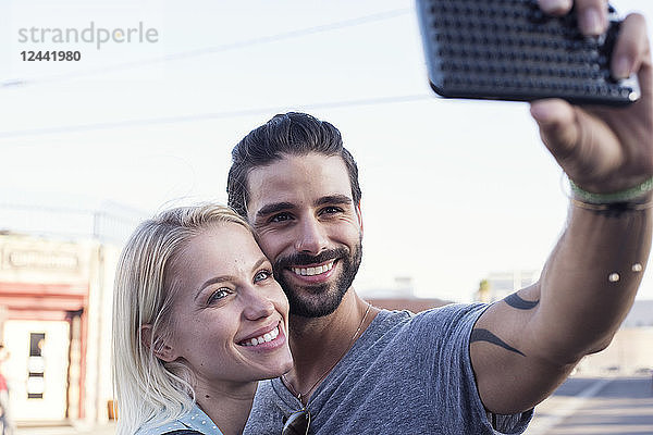 Happy young man with girlfriend taking a selfie
