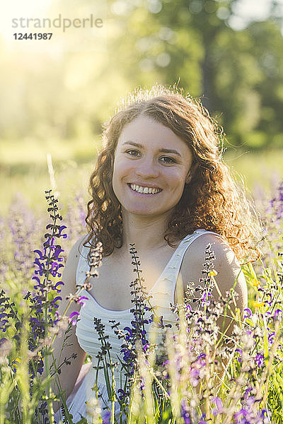 Young woman sitting on summer meadow