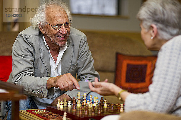 Senior man and woman playing chess in retirement home
