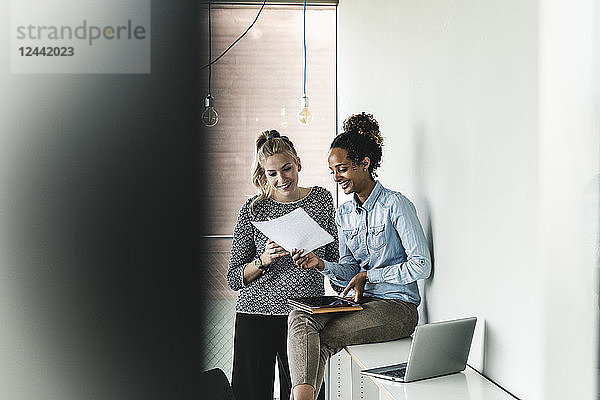 Young women working together in office  reading documents