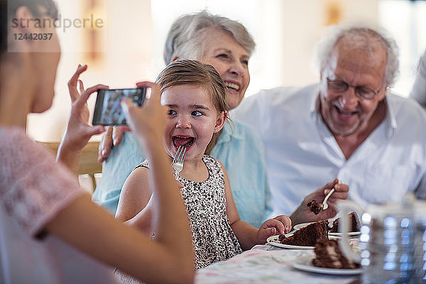 Grandparents celebrating a birthday with their granddaughter  taking picture with smartphone