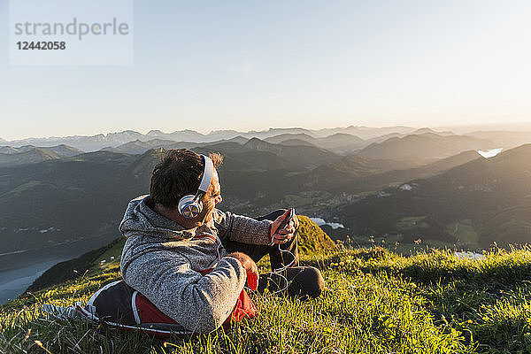 Hiker lying in grass  taking a break and listening music with headphones