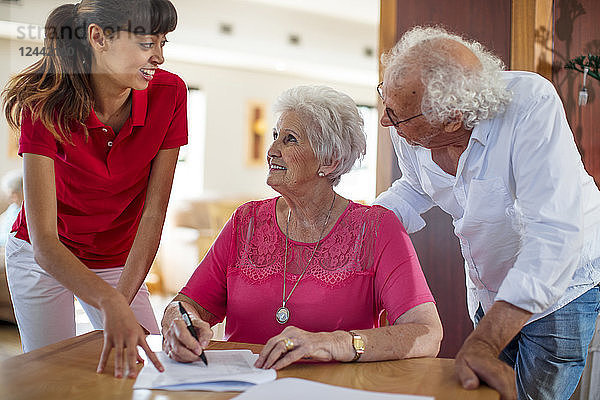 Senior woman signing a contract  nurse and senior man helping her