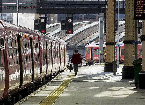 Bahnsteig des Bahnhofs Waterloo mit einem Pendler  der neben dem Zug hergeht; London  England