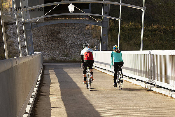 Zwei Radfahrer  die an einem Herbstabend über eine Betonbrücke fahren; Edmonton  Alberta  Kanada